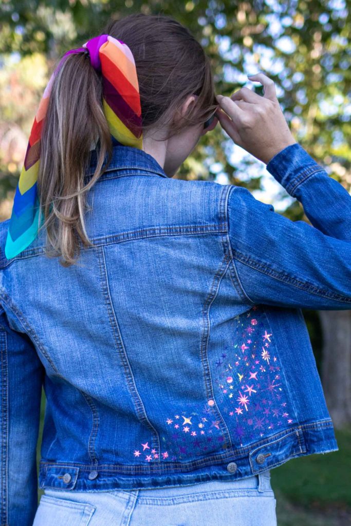 DIY Celestial Holographic Jacket Detail // How to use heat transfer vinyl or holographic iron-on vinyl to make a starry design to update a denim jacket! Download these FREE SVG files for Cricut to make a 90s-inspired holographic denim jacket for the fall // #ad #handmadewithjoann #diystyle #womensfashion #fabricdiy #irononvinyl #holographic #iridescent #freetemplate