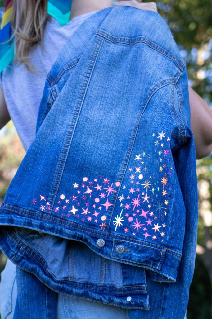 DIY Celestial Holographic Jacket Detail // How to use heat transfer vinyl or holographic iron-on vinyl to make a starry design to update a denim jacket! Download these FREE SVG files for Cricut to make a 90s-inspired holographic denim jacket for the fall // #ad #handmadewithjoann #diystyle #womensfashion #fabricdiy #irononvinyl #holographic #iridescent #freetemplate