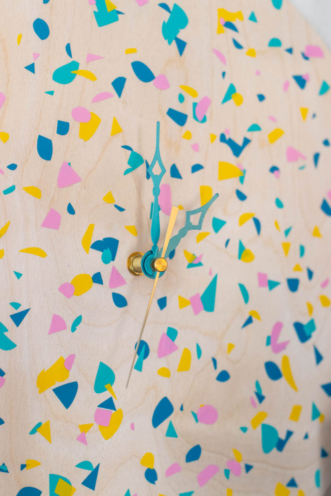 DIY Terrazzo Clock with Vinyl (Free SVG Template!) // Use your Cricut or Silhouette machine to add a colorful terrazzo pattern to a wooden clock with @joann branded adhesive vinyl packs! Simply cut and layer for a unique pieces of wall art using this free cut template! #handmadewithjoann #vinyl #freetemplate #wallart #homedecor #diydecor #terrazzo #cricutmade