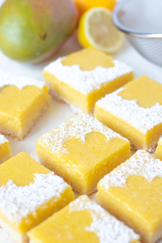 Tart Lemon Mango Bars // Perfectly tart and sweet mango bars with a shortbread cookie crust are the perfect way to celebrate the summer and bring for parties and potluck snacks! Make with fresh mango puree and lemon juice, they're sweet with the perfect amount of bite #mango #fruitbars #shortbread #summertreat #summerrecipes #summerdessert