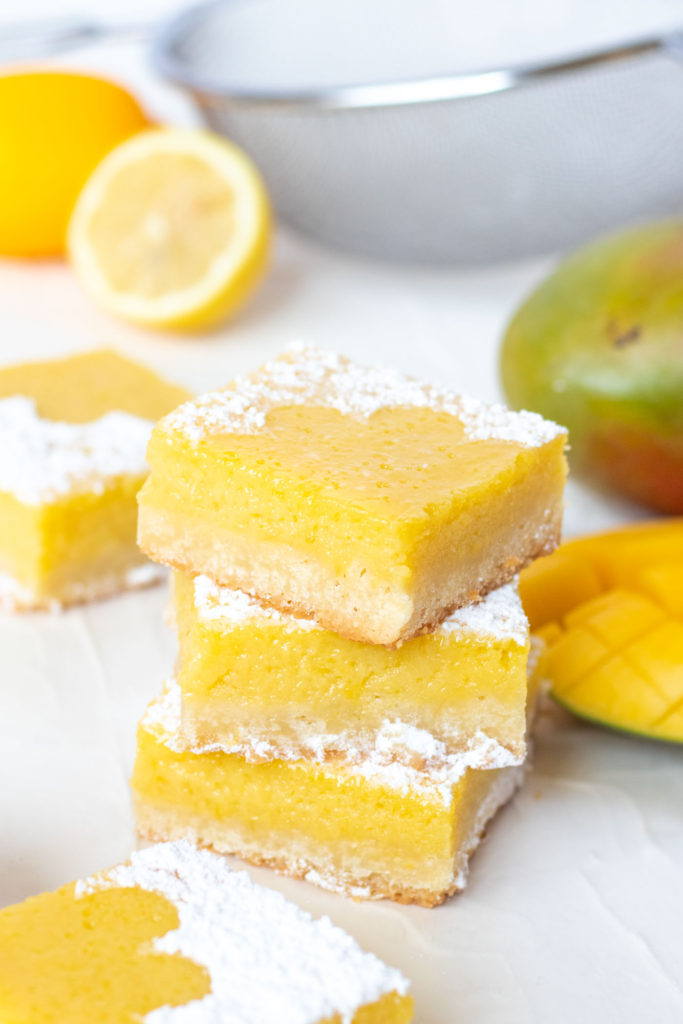 Tart Lemon Mango Bars // Perfectly tart and sweet mango bars with a shortbread cookie crust are the perfect way to celebrate the summer and bring for parties and potluck snacks! Make with fresh mango puree and lemon juice, they're sweet with the perfect amount of bite #mango #fruitbars #shortbread #summertreat #summerrecipes #summerdessert