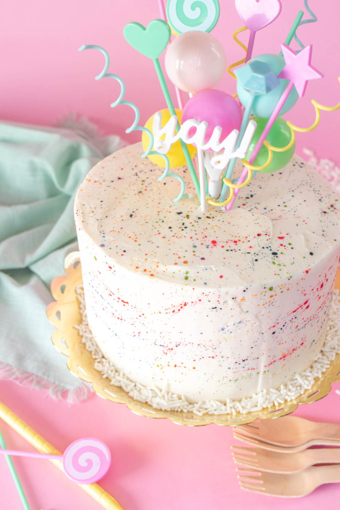 Colorful Splatter Cake // Decorate your favorite cake with splattered food coloring for a fun take on splatter paint designs popular in the 1980s and 90s, perfect for birthdays and other celebrations! #cakedecorating #cake #cakeideas #birthdaycake #birthday #painting #90s #80s