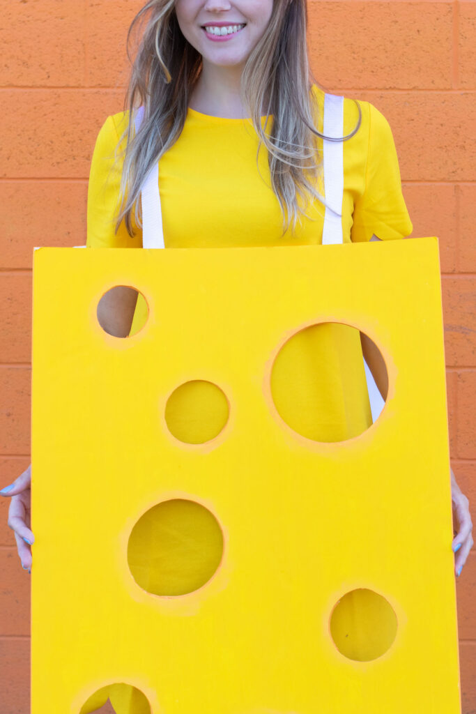 DIY Easy Cheese Costume (Cheeseboard Costume) // Use poster board to make a fun cheesy costume complete with a wedge of cheese headband! This easy last-minute costume is perfect for kids or adults to wear this Halloween #costume #easycostume #diycostume #halloween #adultcostumes #kidscostumes #cheese #posterboard