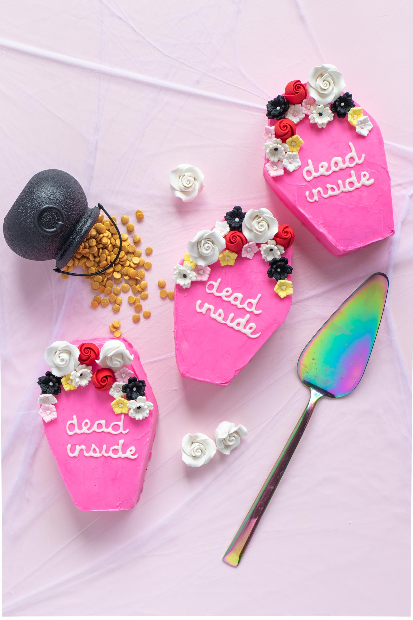 Pink Mini Coffin Cakes for Halloween / Cute mini cakes shaped like coffins, decorated with pink frosting! Add "dead inside" in royal icing and icing flowers for a fun Halloween treat #halloween #halloweendessert #halloweentreat #coffin #frosting #cakedecorating #holidaybaking #halloweenbaking