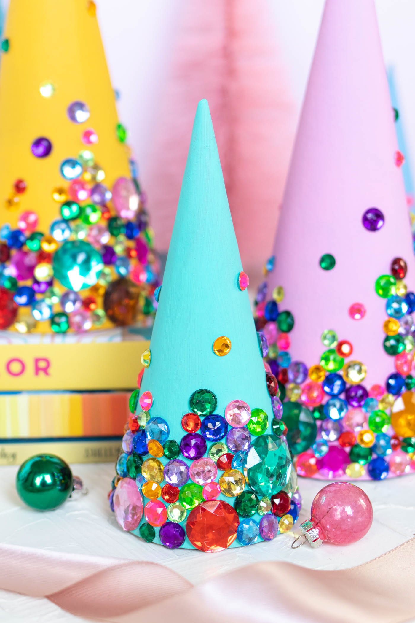 DIY Colorful Rhinestone Tree Decorations // Decorate mache cones with colorful paint and rhinestones to make sparkly tree decorations! These easy DIY Christmas trees make great mantel decor or shelf accessories for the holiday season! #christmasdiy #christmas #christmasdecor #painting #rhinestones #holidaydecor
