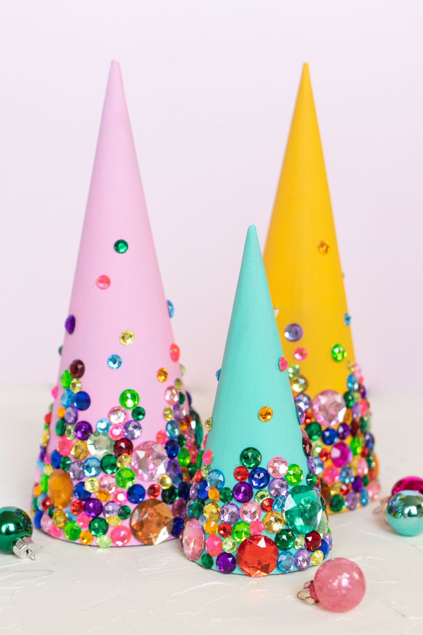 DIY Colorful Rhinestone Tree Decorations // Decorate mache cones with colorful paint and rhinestones to make sparkly tree decorations! These easy DIY Christmas trees make great mantel decor or shelf accessories for the holiday season! #christmasdiy #christmas #christmasdecor #painting #rhinestones #holidaydecor