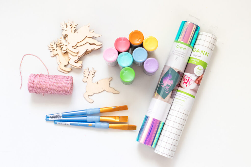 DIY Rainbow Reindeer Garland for Christmas // Paint wooden reindeer ornaments and add holographic vinyl to make a colorful Christmas garland with the names of Santa's reindeer! #christmasdecor #christmas #christmasdiy #rainbowdiy #reindeer #vinyl #cricut #painting