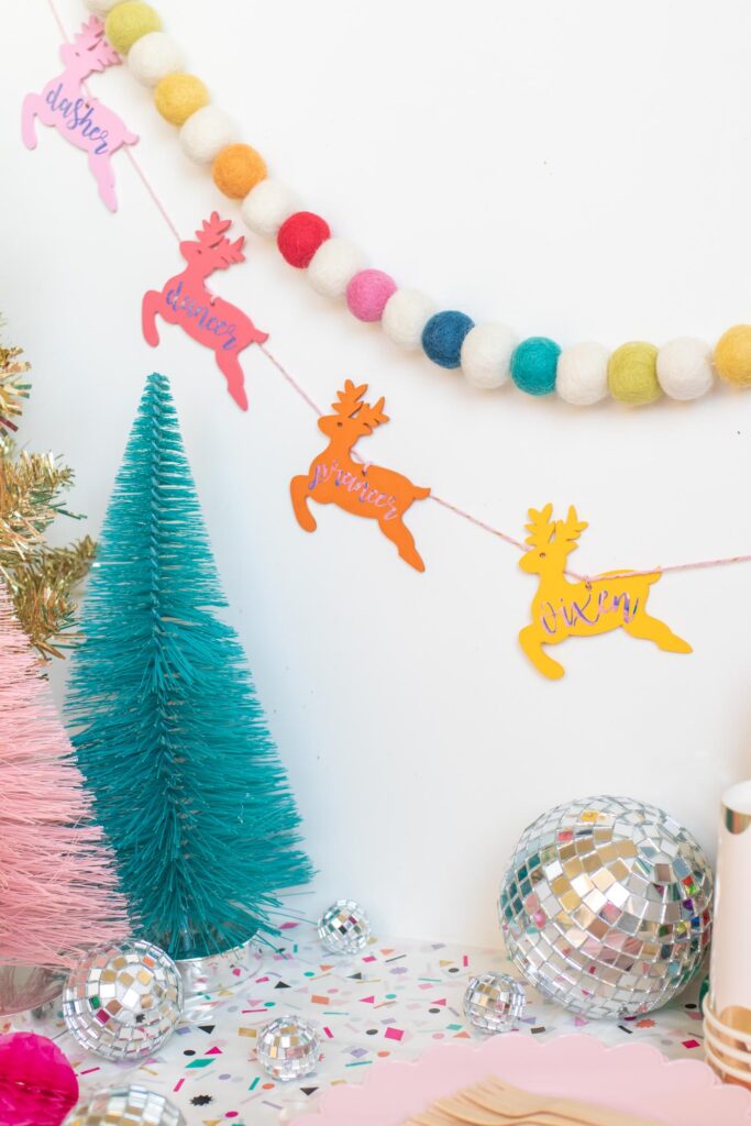DIY Rainbow Reindeer Garland for Christmas // Paint wooden reindeer ornaments and add holographic vinyl to make a colorful Christmas garland with the names of Santa's reindeer! #christmasdecor #christmas #christmasdiy #rainbowdiy #reindeer #vinyl #cricut #painting