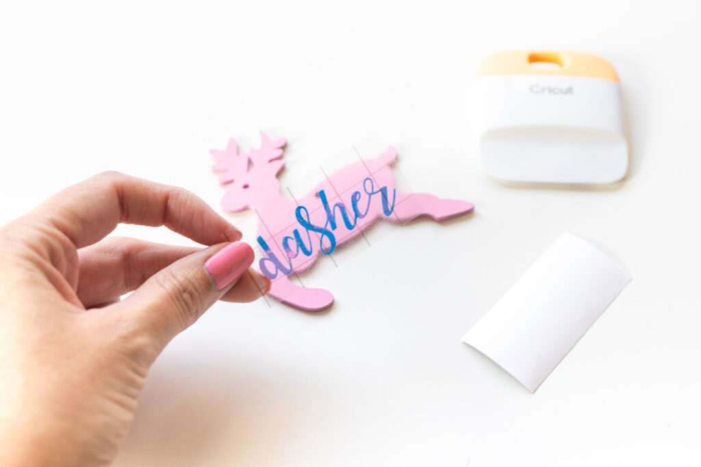 DIY Rainbow Reindeer Garland for Christmas // Paint wooden reindeer ornaments and add holographic vinyl to make a colorful Christmas garland with the names of Santa's reindeer! #christmasdecor #christmas #christmasdiy #rainbowdiy #reindeer #vinyl #cricut #painting