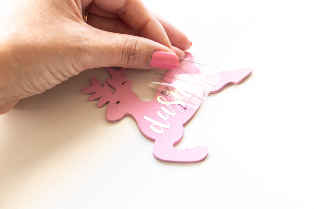 DIY Rainbow Reindeer Garland for Christmas // Paint wooden reindeer ornaments and add holographic vinyl to make a colorful Christmas garland with the names of Santa's reindeer! #christmasdecor #christmas #christmasdiy #rainbowdiy #reindeer #vinyl #cricut #painting