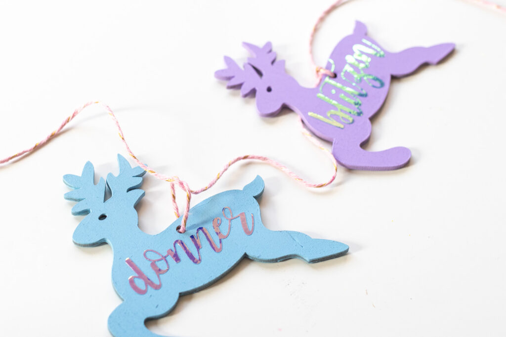 DIY Rainbow Reindeer Garland for Christmas // Paint wooden reindeer ornaments and add holographic vinyl to make a colorful Christmas garland with the names of Santa's reindeer! #christmasdecor #christmas #christmasdiy #rainbowdiy #reindeer #vinyl #cricut #painting