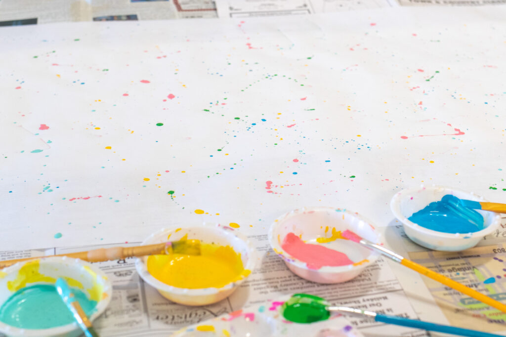 DY Splatter Painted Gift Wrap // Make your own wrapping paper with this simple splatter technique using colorful supplies from @joann! Add 80s and 90s-inspired splatter designs to plain paper for fun DIY gift wrap for Christmas and beyond! #ad #handmadewithjoann #giftwrap #diygiftwrap #wrappingpaper #splatterpaint #painting #rainbow