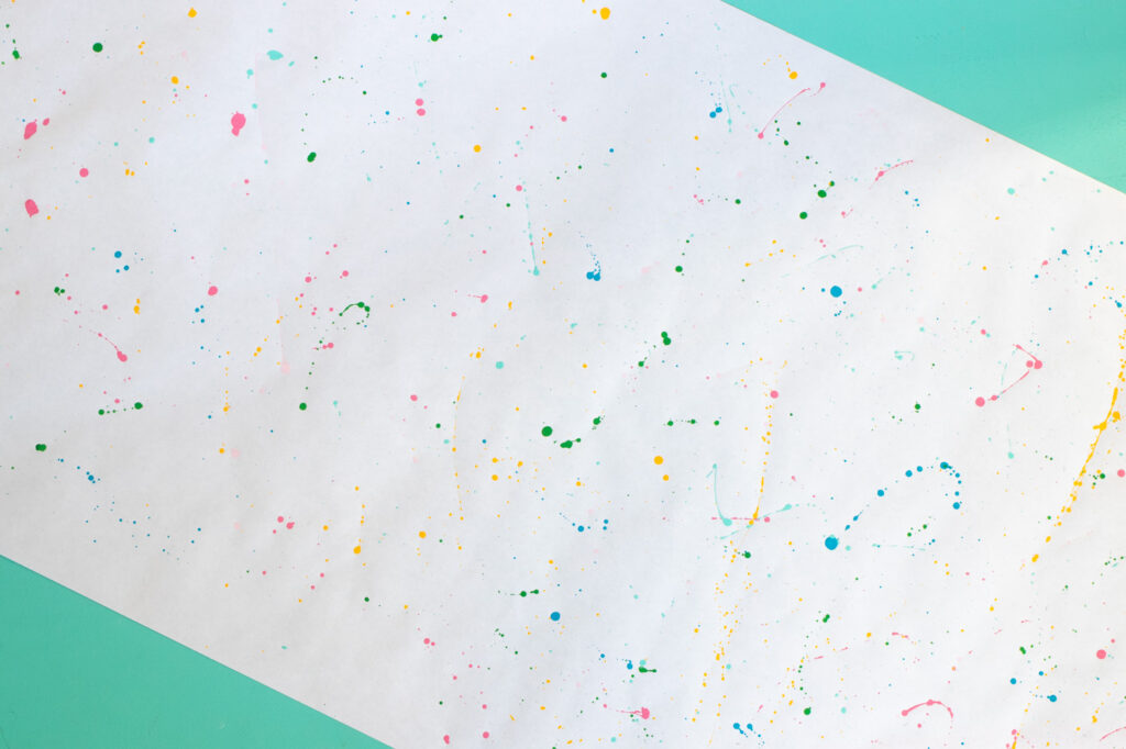 DY Splatter Painted Gift Wrap // Make your own wrapping paper with this simple splatter technique using colorful supplies from @joann! Add 80s and 90s-inspired splatter designs to plain paper for fun DIY gift wrap for Christmas and beyond! #ad #handmadewithjoann #giftwrap #diygiftwrap #wrappingpaper #splatterpaint #painting #rainbow