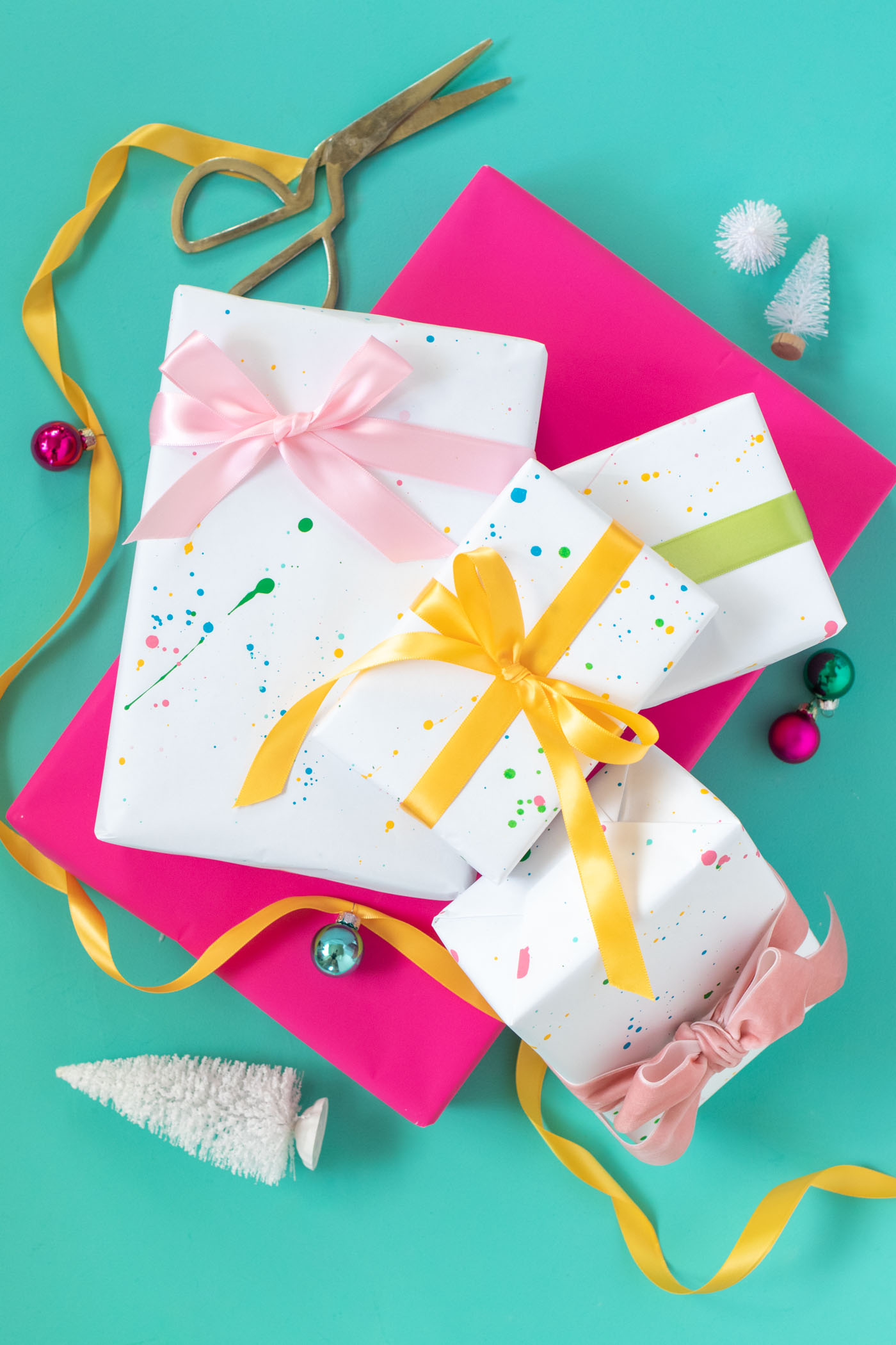 DY Splatter Painted Gift Wrap // Make your own wrapping paper with this simple splatter technique using colorful supplies from @joann! Add 80s and 90s-inspired splatter designs to plain paper for fun DIY gift wrap for Christmas and beyond! #ad #handmadewithjoann #giftwrap #diygiftwrap #wrappingpaper #splatterpaint #painting #rainbow