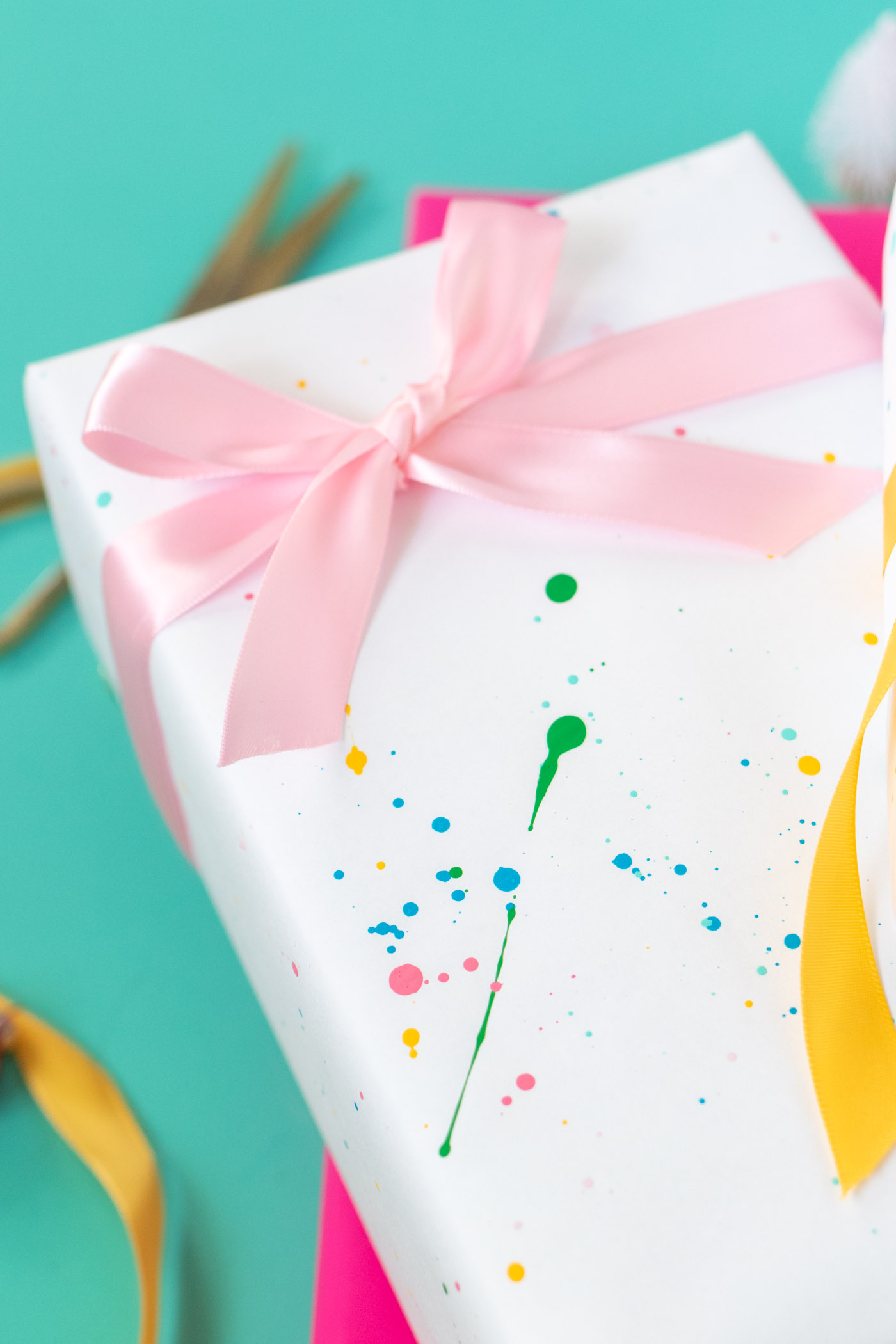 DY Splatter Painted Gift Wrap // Make your own wrapping paper with this simple splatter technique using colorful supplies from @joann! Add 80s and 90s-inspired splatter designs to plain paper for fun DIY gift wrap for Christmas and beyond! #ad #handmadewithjoann #giftwrap #diygiftwrap #wrappingpaper #splatterpaint #painting #rainbow