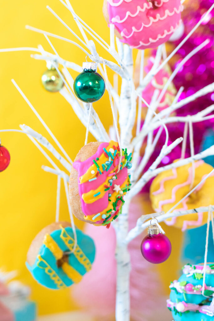Edible Donut Ornaments // Decorate a Christmas tree or branches with these colorful edible donut ornaments! Display holiday donuts on a tree for a fun party treat or just for a fun weekend project #donuts #holidaydesserts #christmas #christmasfood #christmasparty #partyfood #donutdecorating #candymelts #christmasdecor #diychristmas