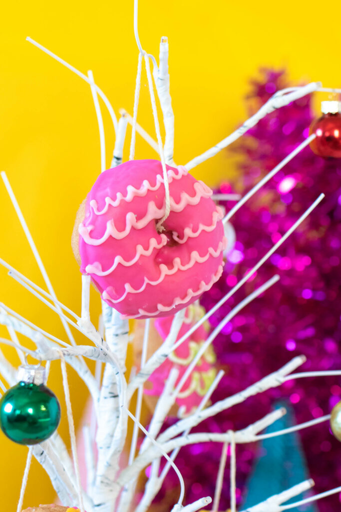 Edible Donut Ornaments // Decorate a Christmas tree or branches with these colorful edible donut ornaments! Display holiday donuts on a tree for a fun party treat or just for a fun weekend project #donuts #holidaydesserts #christmas #christmasfood #christmasparty #partyfood #donutdecorating #candymelts #christmasdecor #diychristmas
