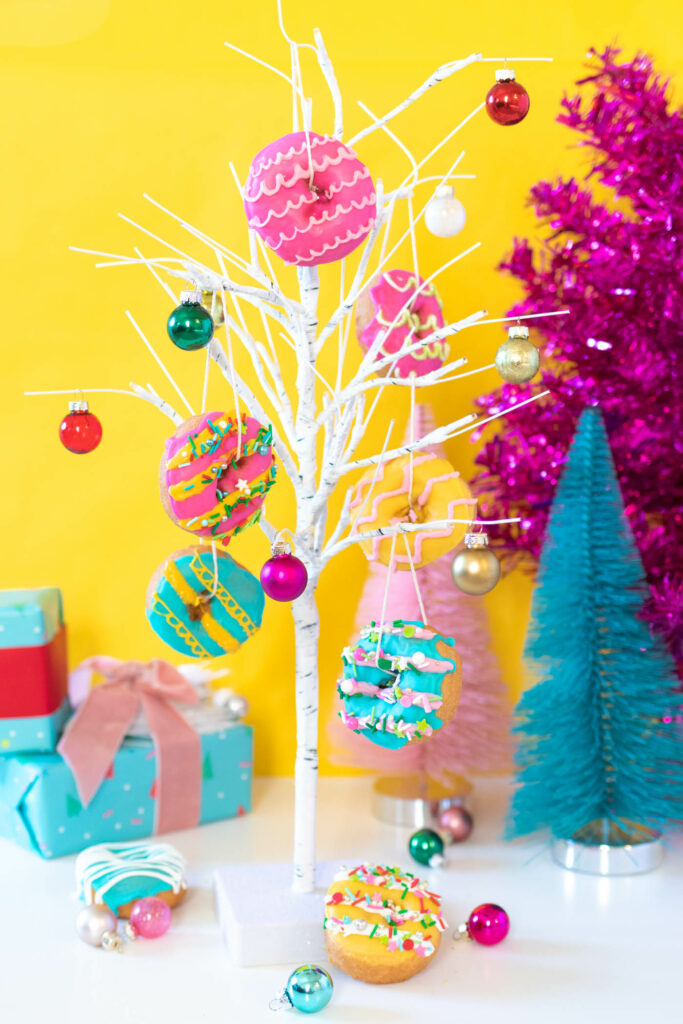 Edible Donut Ornaments // Decorate a Christmas tree or branches with these colorful edible donut ornaments! Display holiday donuts on a tree for a fun party treat or just for a fun weekend project #donuts #holidaydesserts #christmas #christmasfood #christmasparty #partyfood #donutdecorating #candymelts #christmasdecor #diychristmas