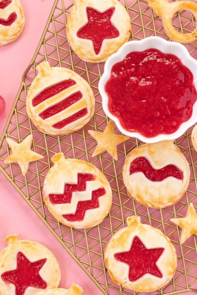 Ornament Pies // Christmas Hand Pies // Cut pie dough into ornament shapes with cut-out details for making cute mini Christmas pies! Fill with colorful cherry pie filling for a great holiday treat or after-dinner Christmas dessert #christmasrecipe #pie #handpies #christmasdessert #pierecipe #cookiecutters #diyornaments