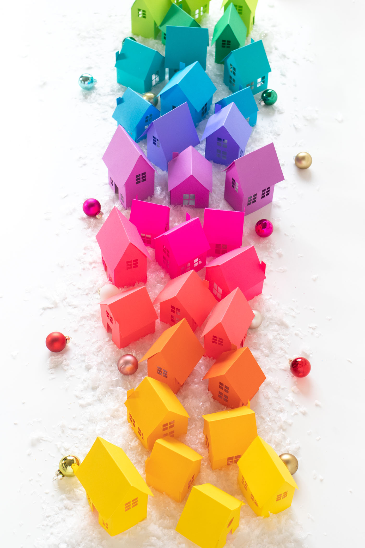 Rainbow Holiday Village with Paper + Free Templates for Cricut or Silhouette! // Decorate for Christmas with these paper houses made with vibrant Astrobrights cardstock! Turn the holiday village into a rainbow surrounded by fake snow, bottlebrush trees, and LED lights for a festive holiday display! #christmas #christmasdecor #diychristmas #holidayseason #holidaydecor #rainbow #papercrafts #freetemplate #freeprintable