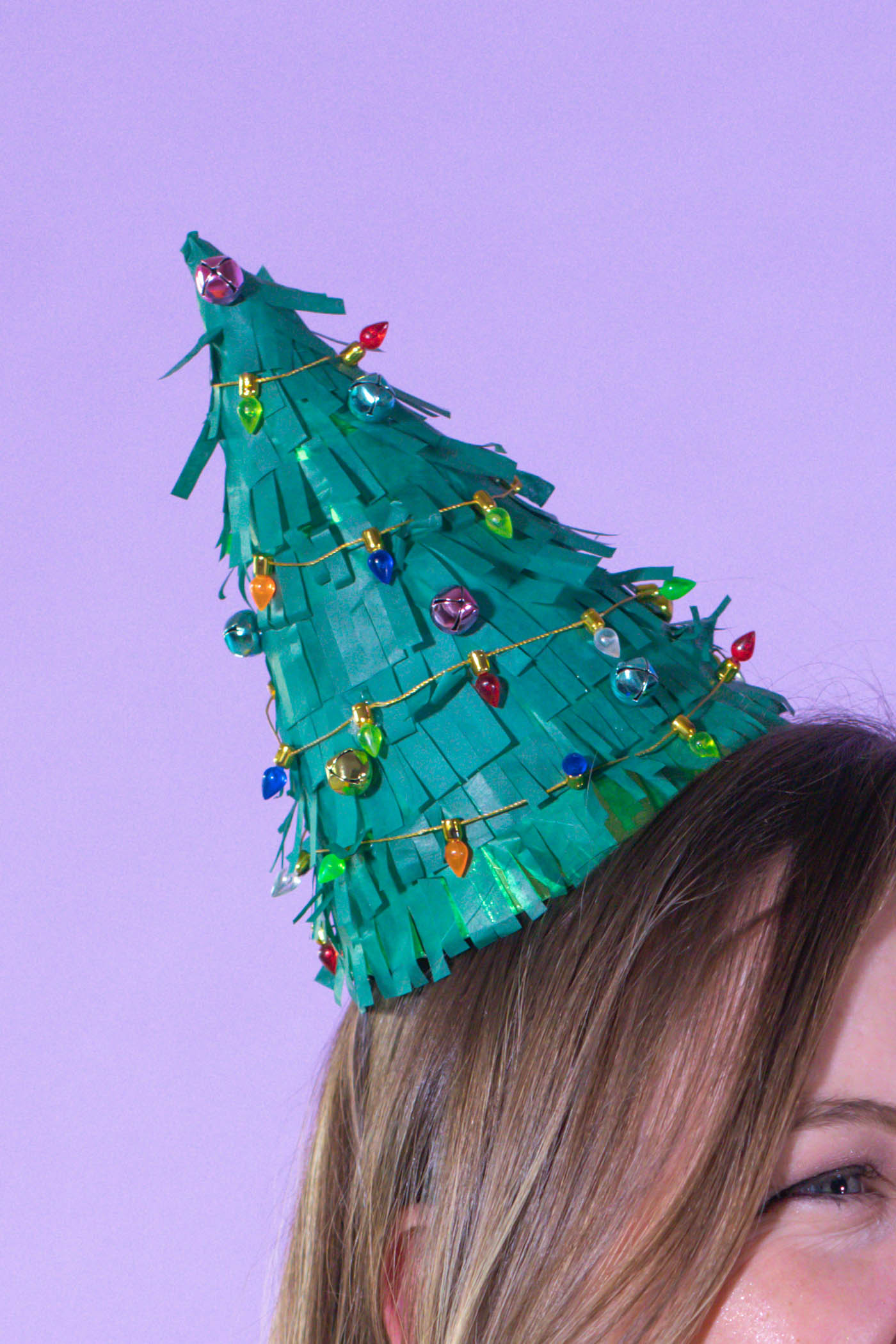 DIY Christmas Tree Party Hats // Turn a plain party hat into a fun holiday craft with tissue paper! Upcycle your hats into fringed Christmas trees decorated with lights and ornaments! #christmas #christmasdiy #christmascrafts #partydiy #partyideas #holidayparty #christmasparty #partyhats