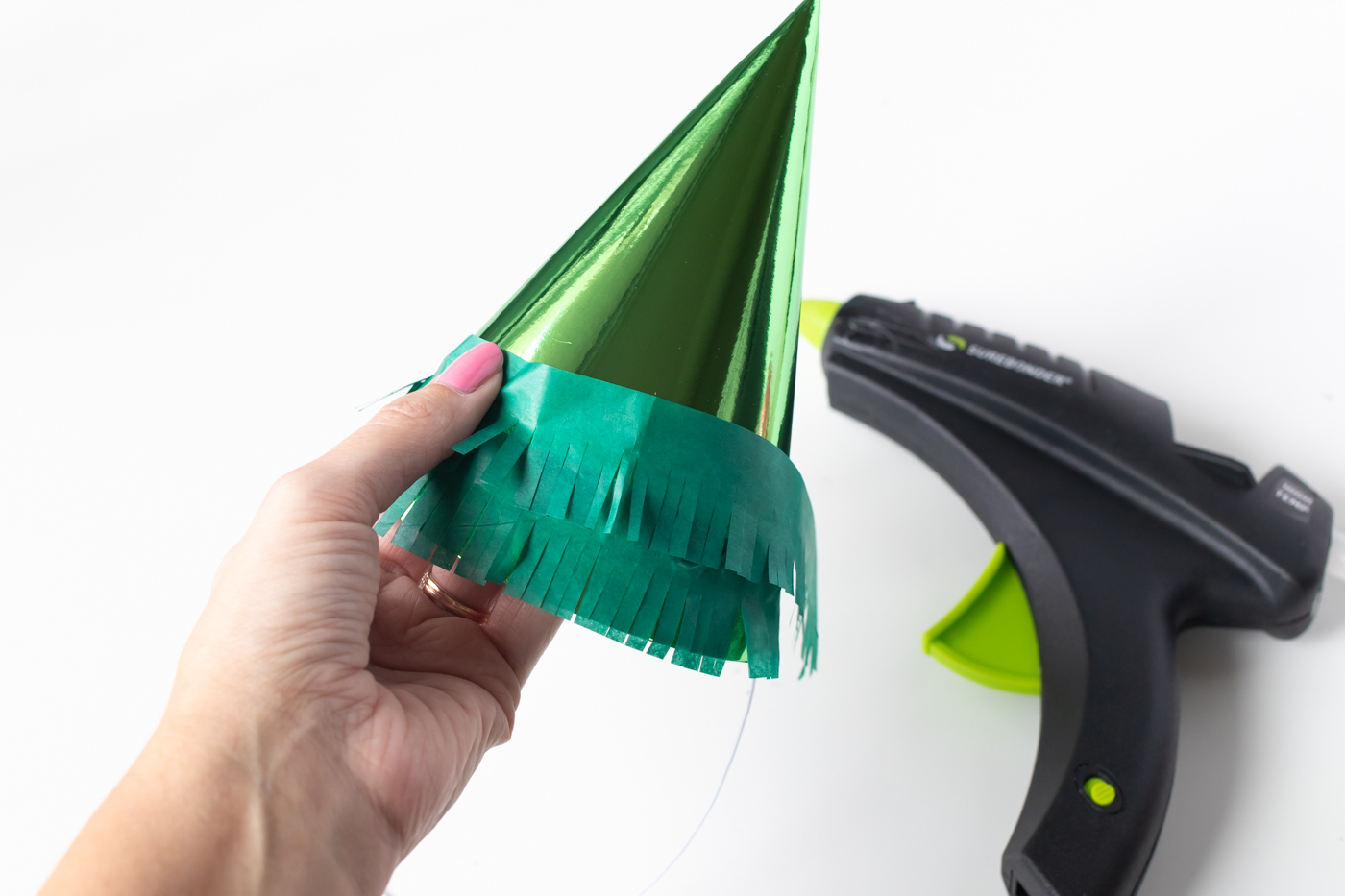 DIY Christmas Tree Party Hats // Turn a plain party hat into a fun holiday craft with tissue paper! Upcycle your hats into fringed Christmas trees decorated with lights and ornaments! #christmas #christmasdiy #christmascrafts #partydiy #partyideas #holidayparty #christmasparty #partyhats