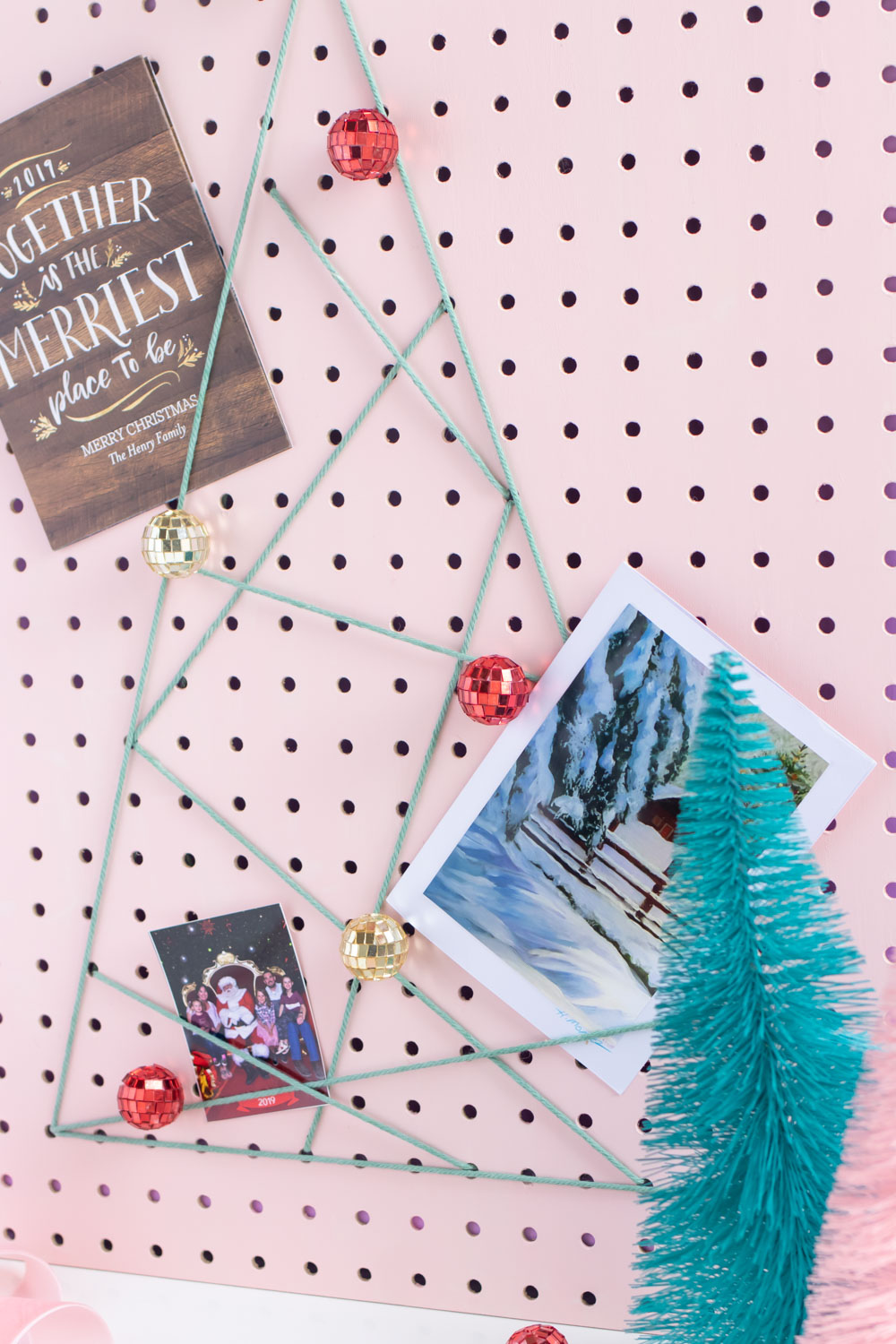 DIY Holiday Pegboard Card Holder // Turn a slab of pegboard into a fun Christmas tree card display inspired by string art! Display your holiday cards in a unique way with this DIY Christmas decor idea #christmasdiy #christmascard #christmasdecor #christmasstorage #pegboard #papercrafts #stringart #holidaystorage #cardstorage