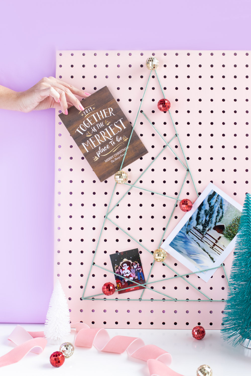 DIY Holiday Pegboard Card Holder // Turn a slab of pegboard into a fun Christmas tree card display inspired by string art! Display your holiday cards in a unique way with this DIY Christmas decor idea #christmasdiy #christmascard #christmasdecor #christmasstorage #pegboard #papercrafts #stringart #holidaystorage #cardstorage