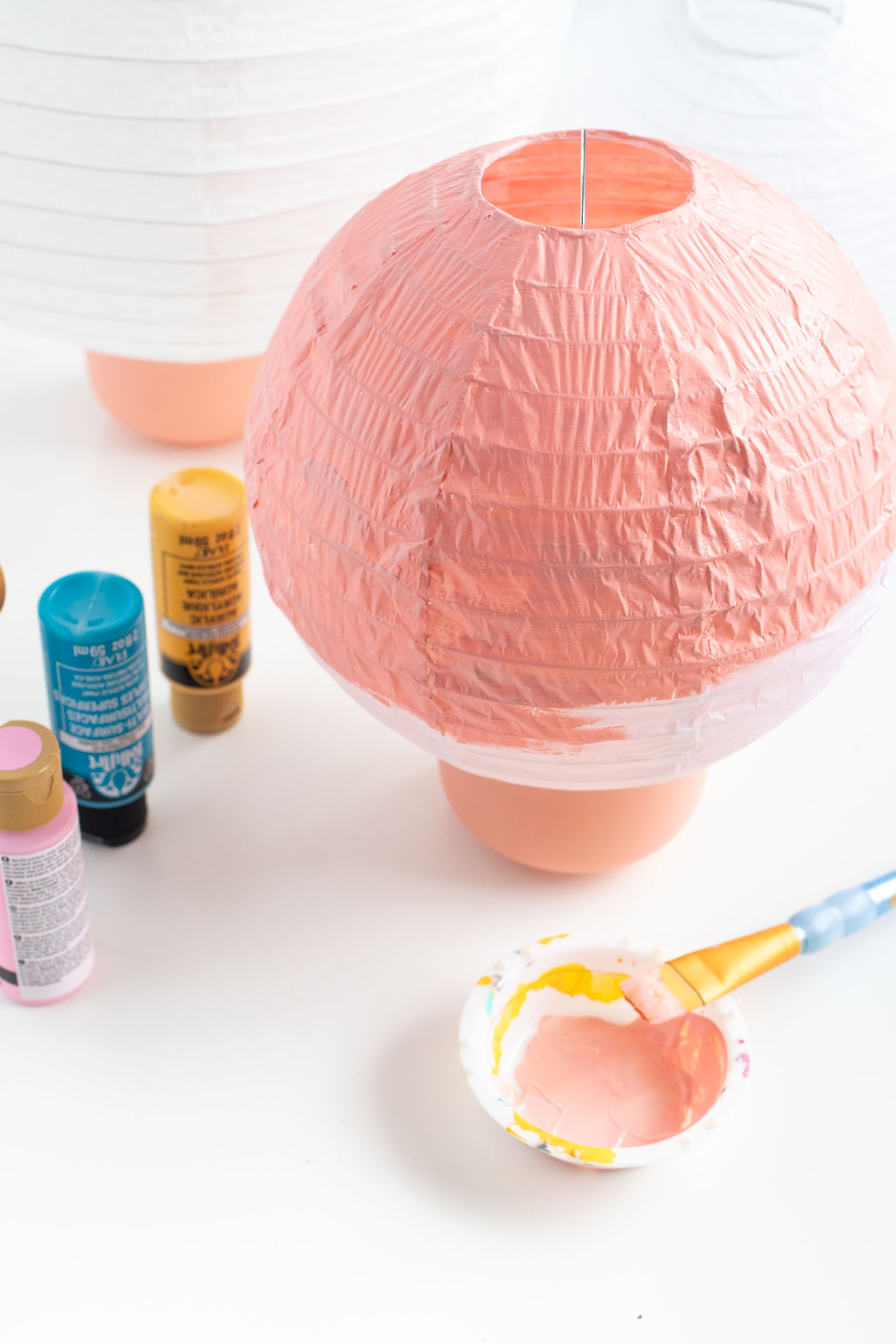 DIY Ornament Lanterns // Turn plain white lanterns into colorful ornament decor with this easy Christmas DIY! Paint lanterns and add tops to make them look like oversized ornaments for your holiday decor! #christmas #christmasdiy #painting #lanterns #papercrafts #homedecor #easydiy #upcycling