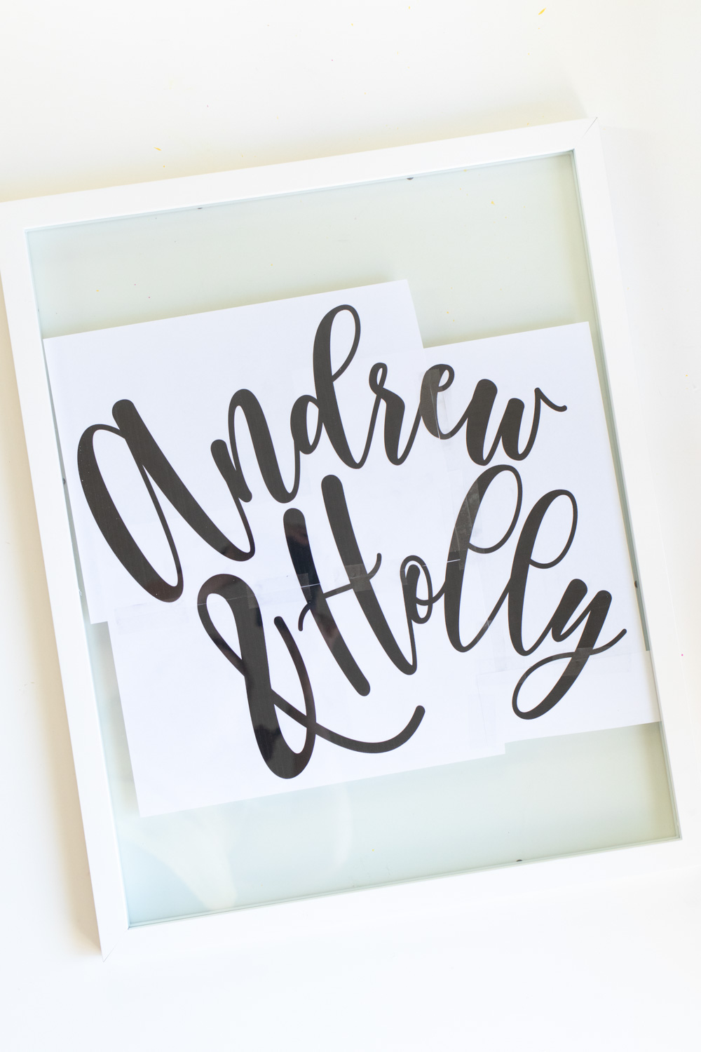 Easy DIY Calligraphy Wedding Sign // Use a large photo frame to make your own custom wedding signage with Rust-Oleum spray paints! Trace your names or sayings, then let it pop off the glass with the new Imagine collection of glitter spray paint available at @joann! #ad #handmadewithjoann #weddingdiy #diywedding #weddingsign #spraypainting #calligraphy #diyideas #homedecor
