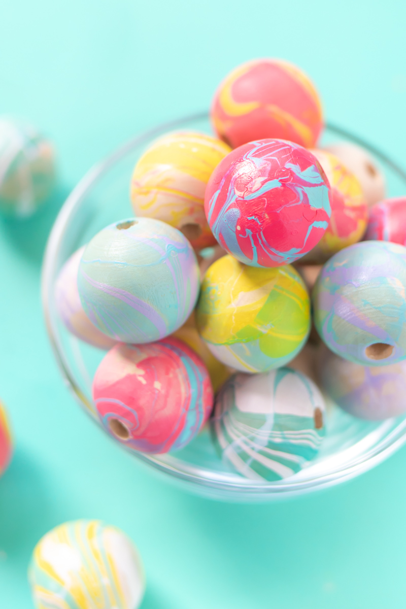 How to Nail Polish Marble Beads for Jewelry // Check out this guide to nail polish marbling with tips and tricks for creating marbled effects on almost any object! Make colorful marbled beads for jewelry, garlands and more! #budgetdiy #diyjewelry #marbled #nailpolish #nailart #painting #diyideas #diysforteens