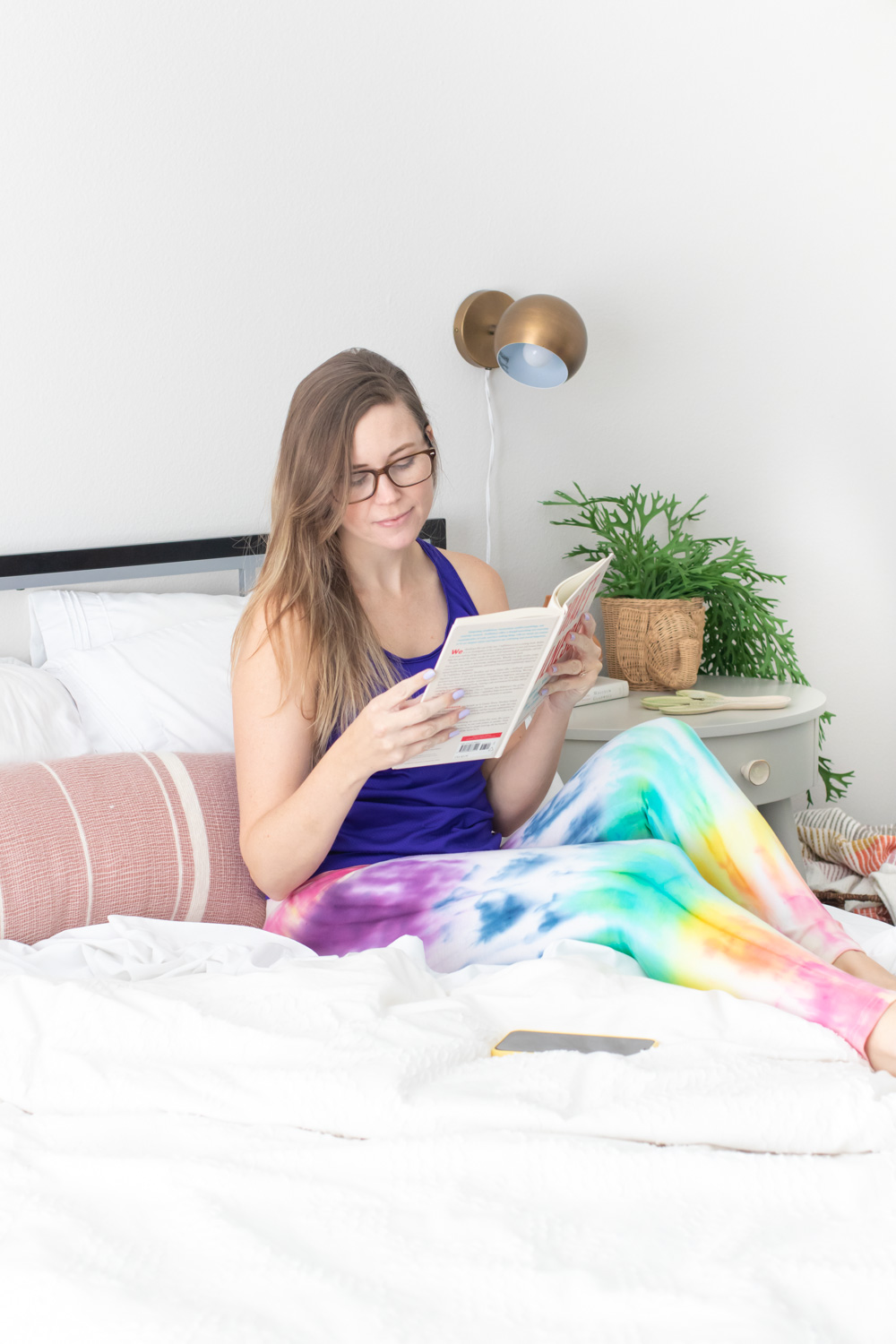 woman reading in bed wearing rainbow tie dye leggings