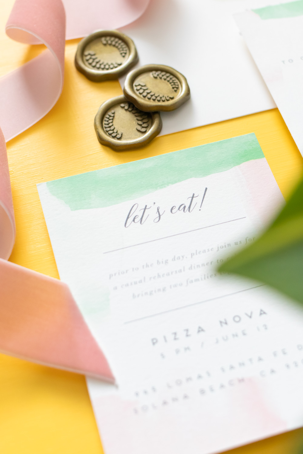 Closeup of rehearsal dinner invitations on yellow background