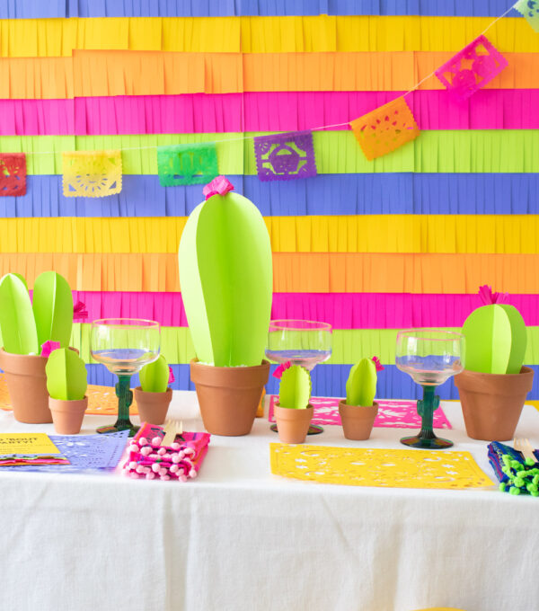 colorful paper fiesta decor table with fringe backdrop, paper cacti