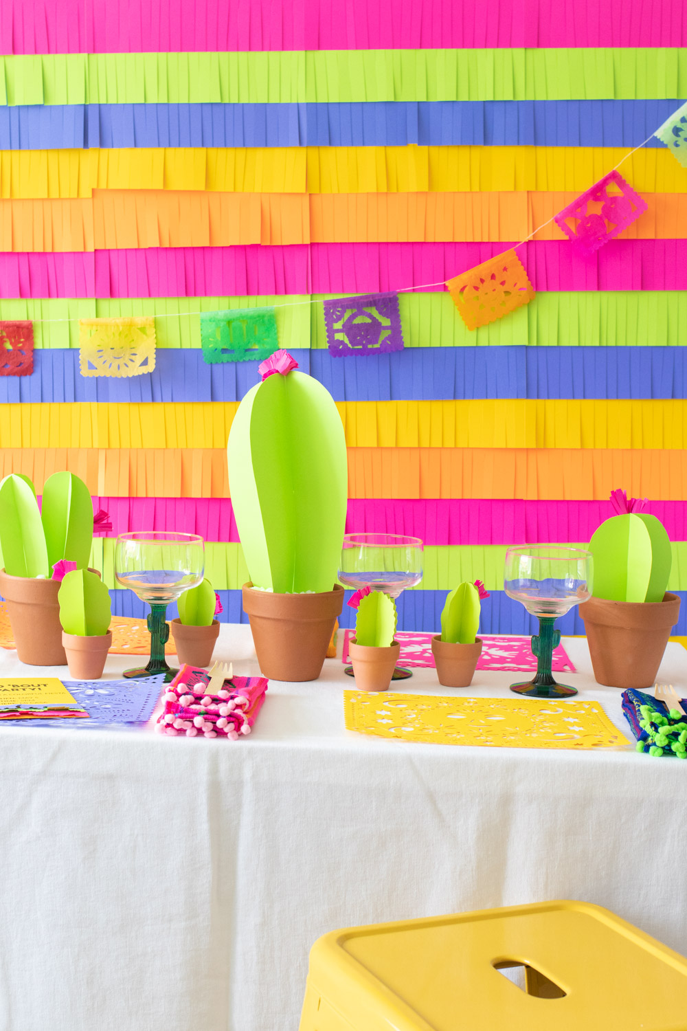 colorful paper fiesta decor table with fringe backdrop, paper cacti