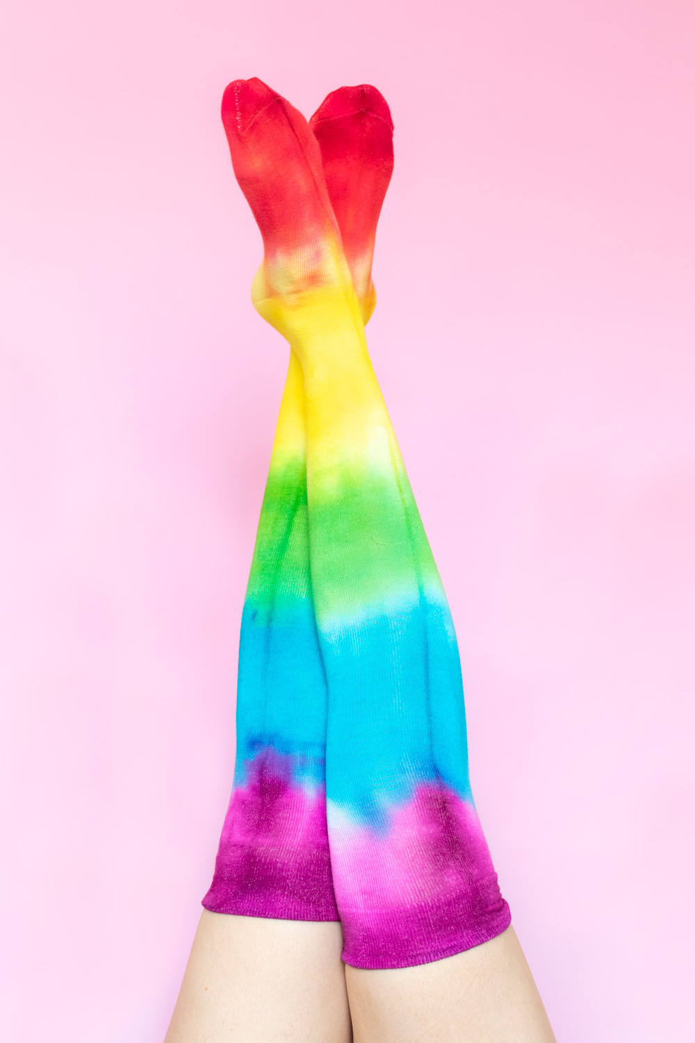 crossed legs wearing rainbow socks against pink