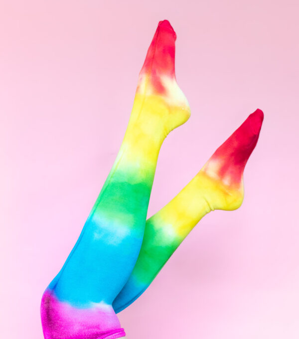 legs in air wearing tie dye socks on pink background
