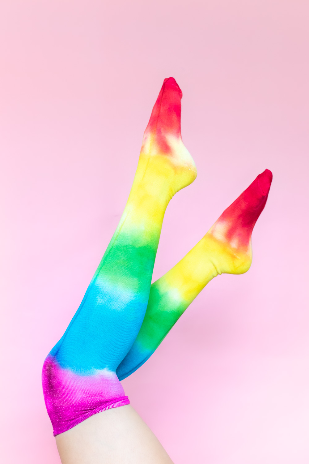 legs in air wearing tie dye socks on pink background