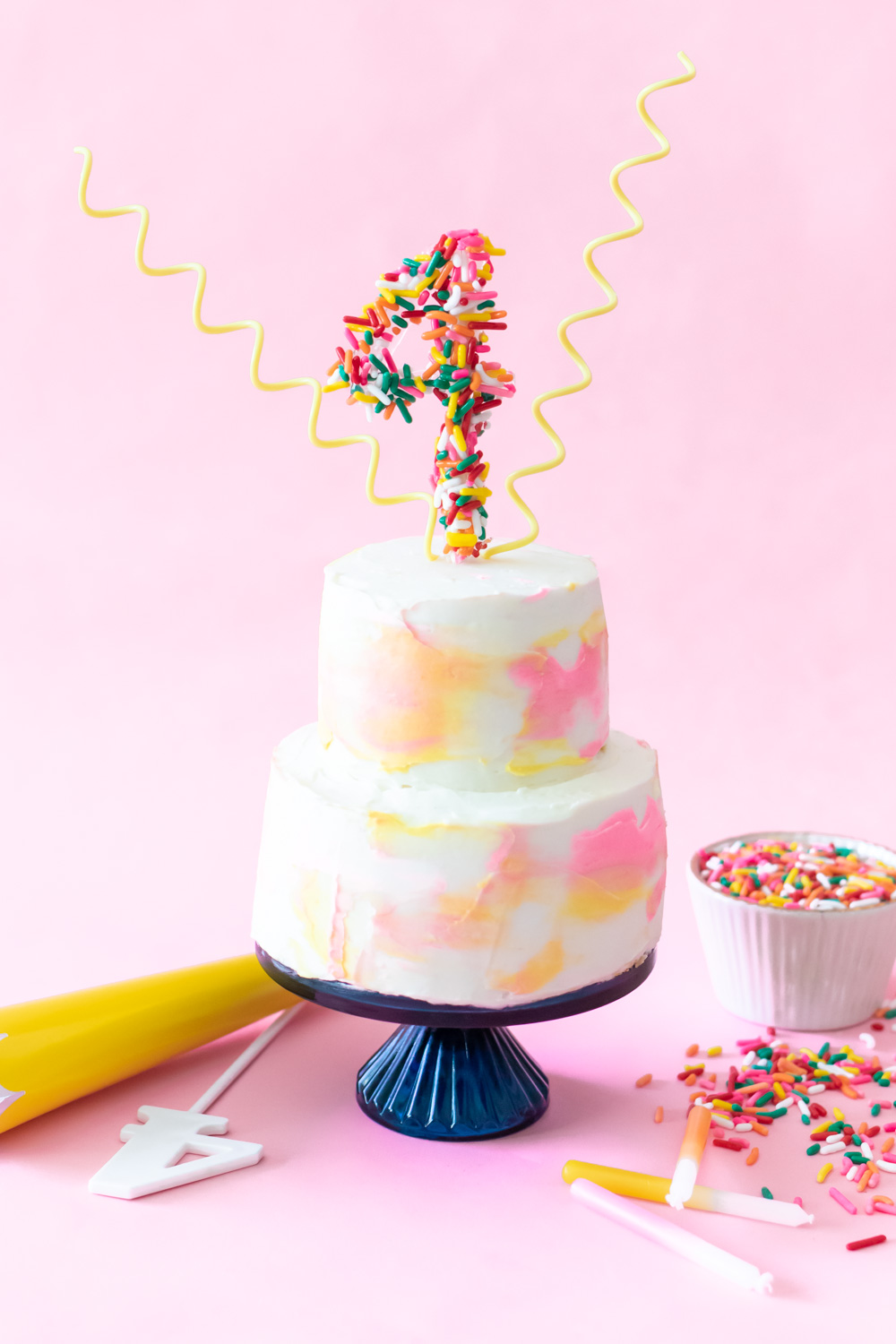 miniature cake with sprinkle number topper on pink