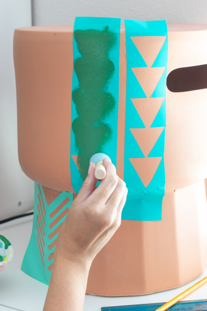 dabbing paint onto geometric vinyl stencil for making stenciled side table
