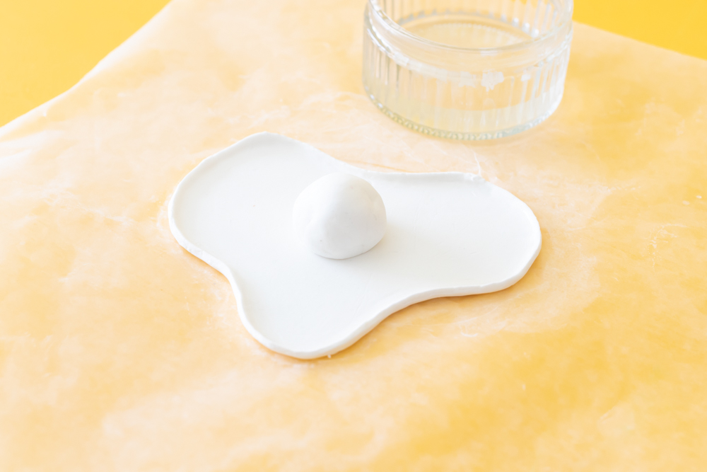 ball of clay in the middle of a wavy dish