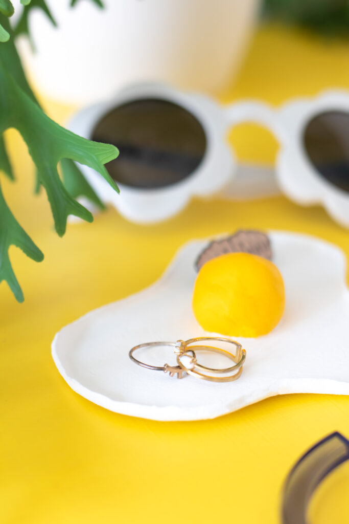 side view of fried egg clay trinket dish with rings and sunglasses