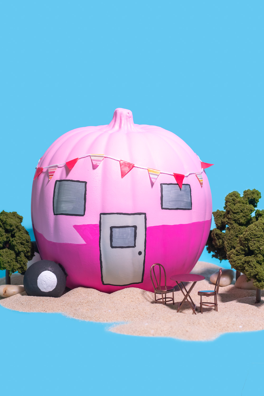 colorful vintage trailer pumpkin on blue background with sand and trees