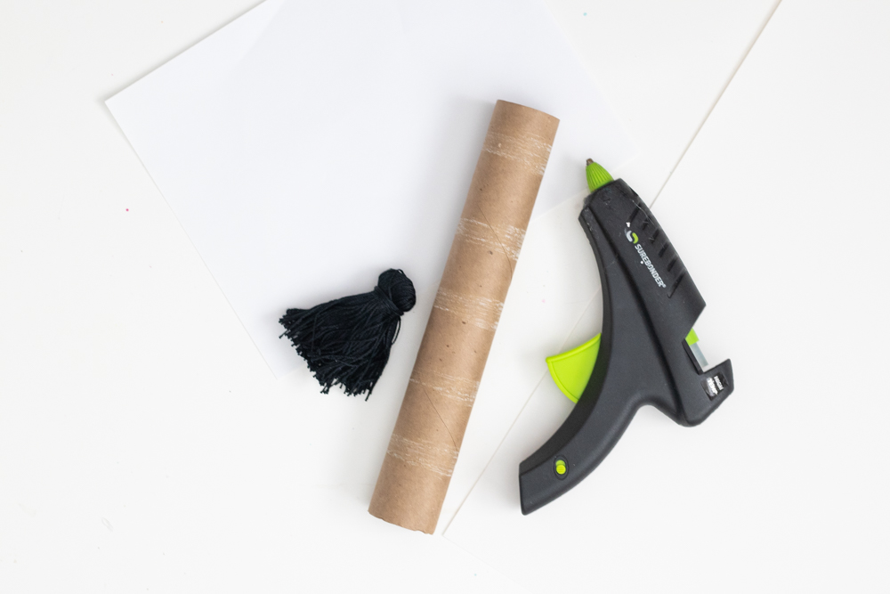 toilet paper roll, tassel and glue gun for DIY Halloween costume