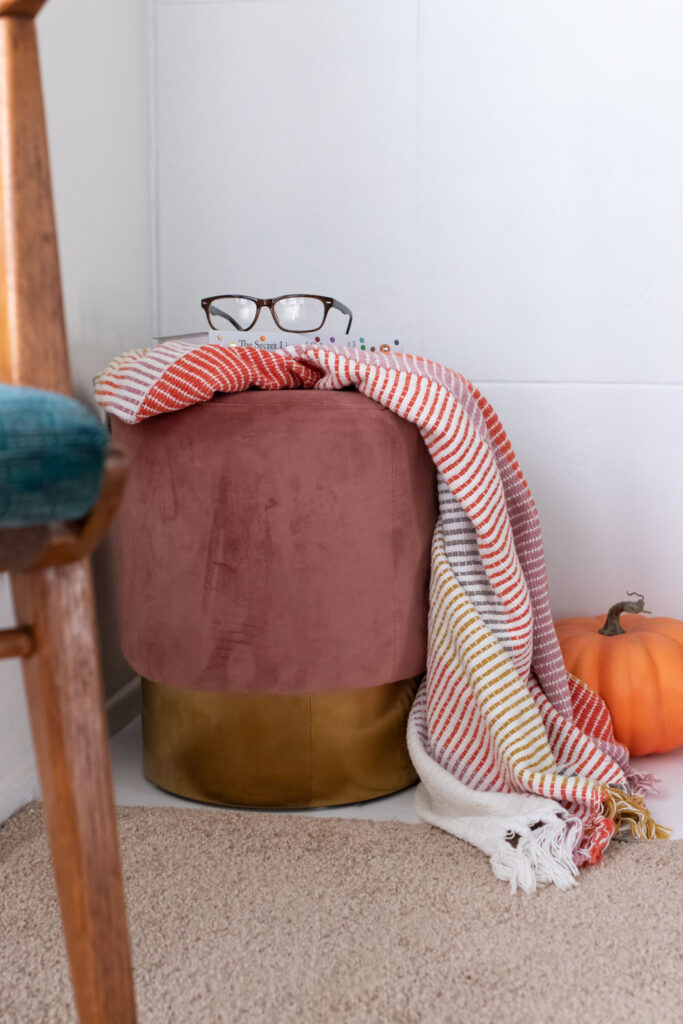 ottoman and blanket next to white fireplace