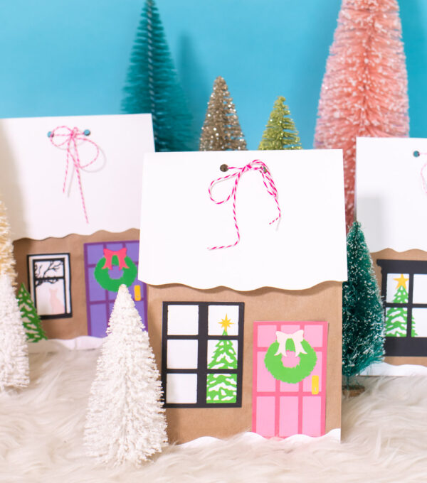 assortment of gingerbread house paper gift bags surrounded by bottlebrush trees