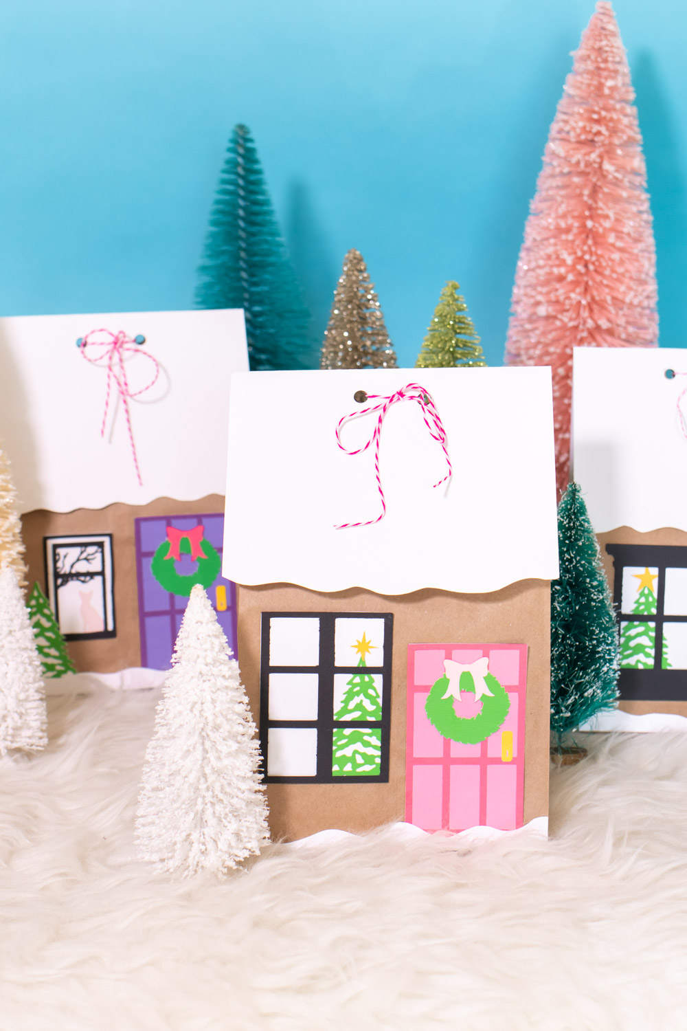 assortment of gingerbread house paper gift bags surrounded by bottlebrush trees