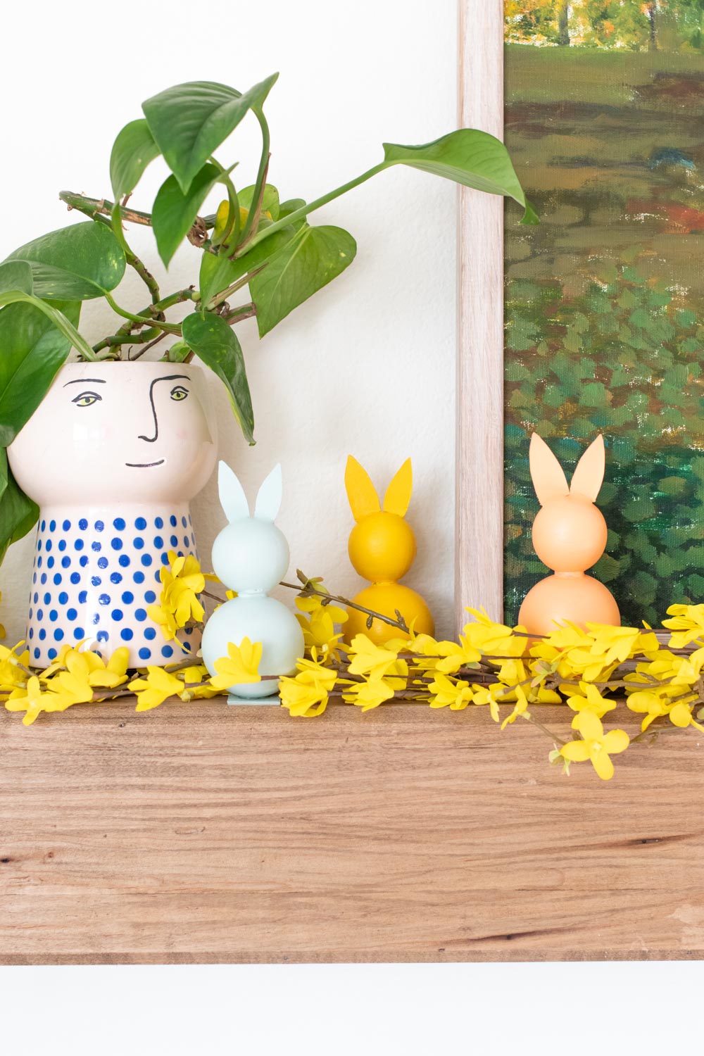 three modern easter decor bunnies on a mantel with a plant