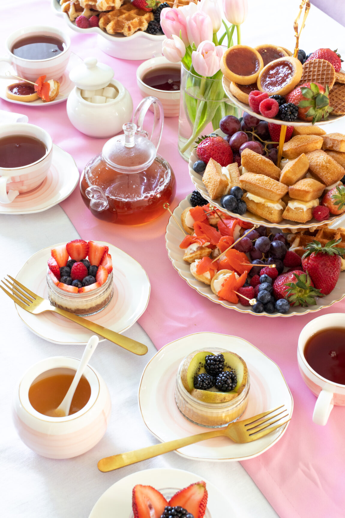 tablescape of spring tea party decor with cheesecakes and cookies