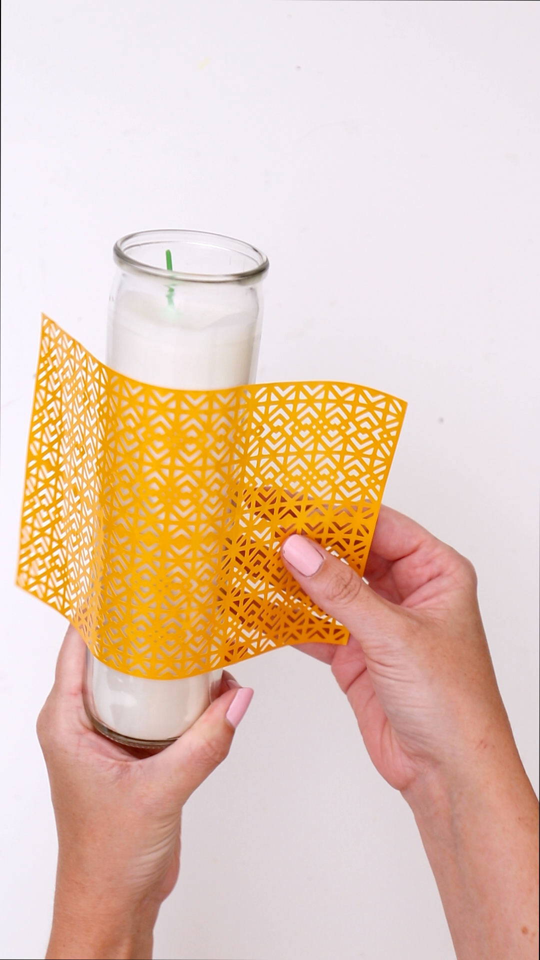 applying intricate cricut vinyl design to candleholder